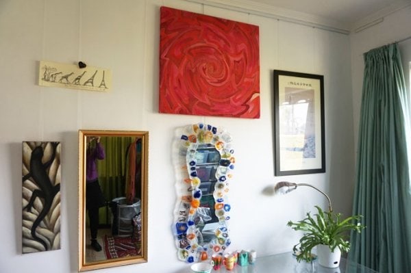 colourful art and mirrors hung on wall with picture hanging rail
