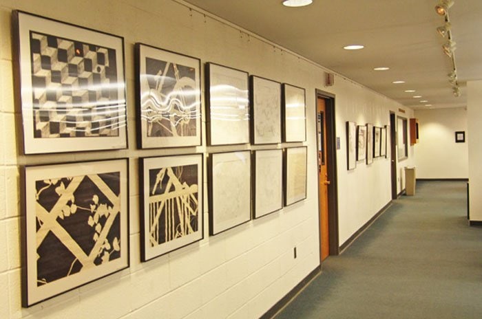 artiteq-picture-rails-brick-wall-hang-logic two rows of framed artworks hung on a brick wall with an art hanging system