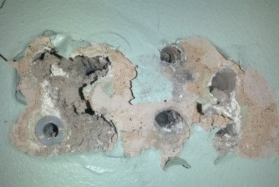 Severe wall damage with multiple holes caused by screws, illustrating the drawbacks of traditional hanging methods.
