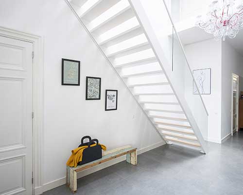 Sloped-Wall-Picture-Rail-at-HANG-LOGIC Artiteq Picture Rail installed on a sloping wall in a staircase, featuring a lockable stopper, available at Hang Logic."